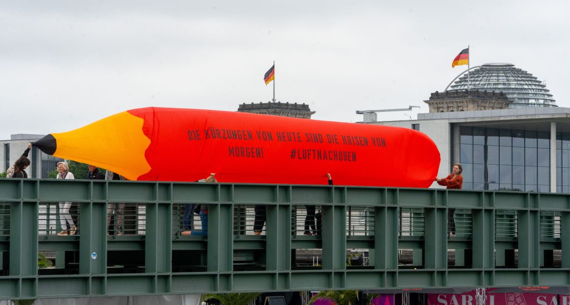 Ein mit Luft gefüllter übergroßer Bleistift wird von Protestlern über eine Brücke im Regierungsviertel Berlins getragen