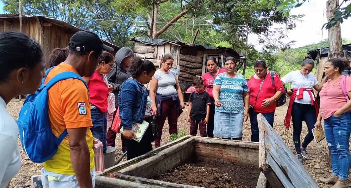 Gruppe von Menschen steht um einen Komposthaufen.