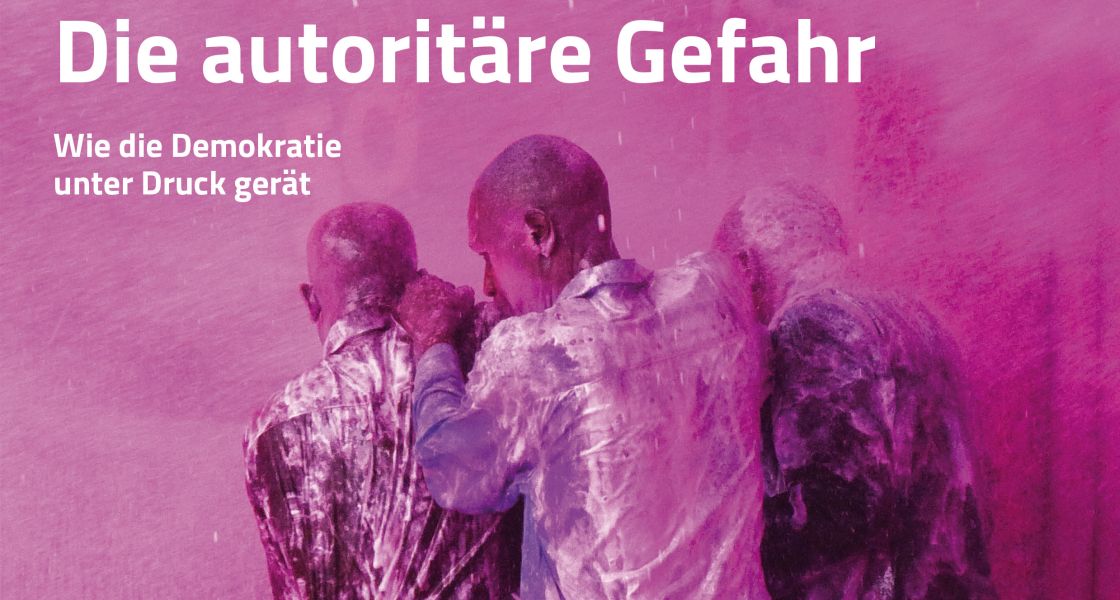 Drei Männer halten sich gegenseitig fest und schützen sich vor Rosa Partikelchen in der Luft