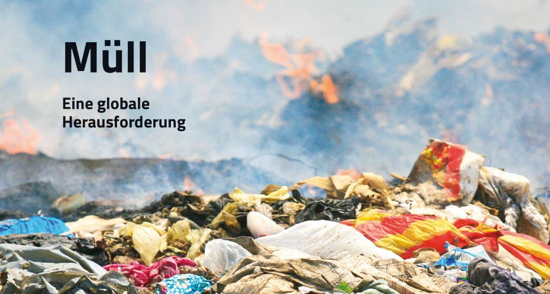 Ein großer Berg mit Plastikbeuteln, im Hintergrund brennt ein Müllberg