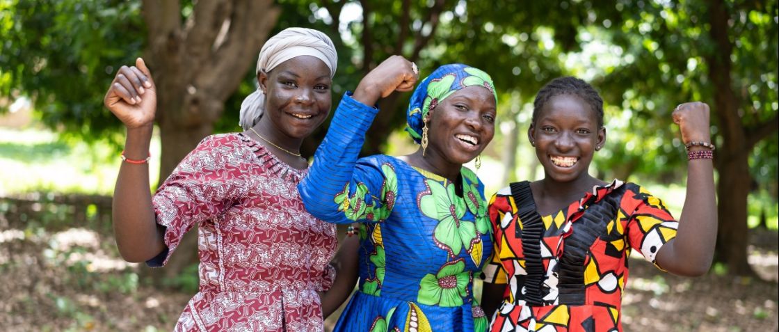 Drei Frauen stehen zusamemn und halten je eine Faust hoch und lachen