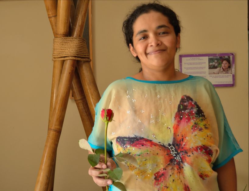 Portrait von María Teresa Rivera, die in der Hand eine Rose hält und lächelt.