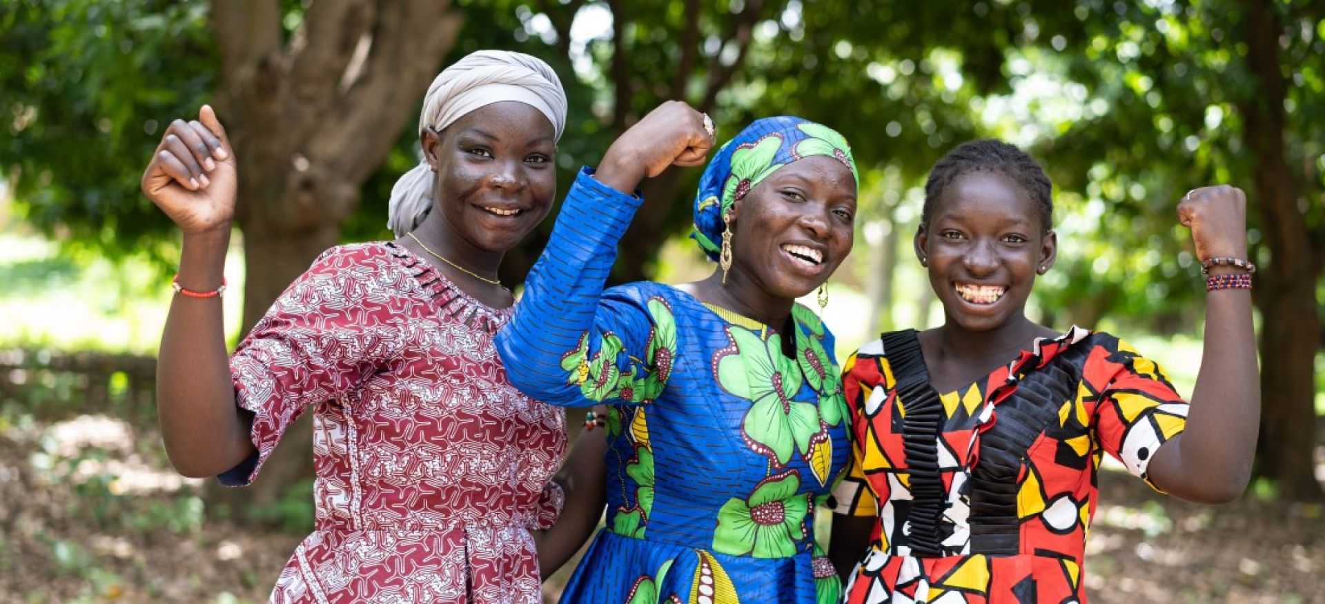 Drei Frauen stehen zusamemn und halten je eine Faust hoch und lachen