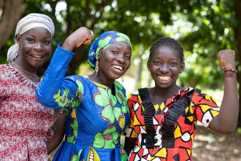 Drei Frauen stehen zusamemn und halten je eine Faust hoch und lachen