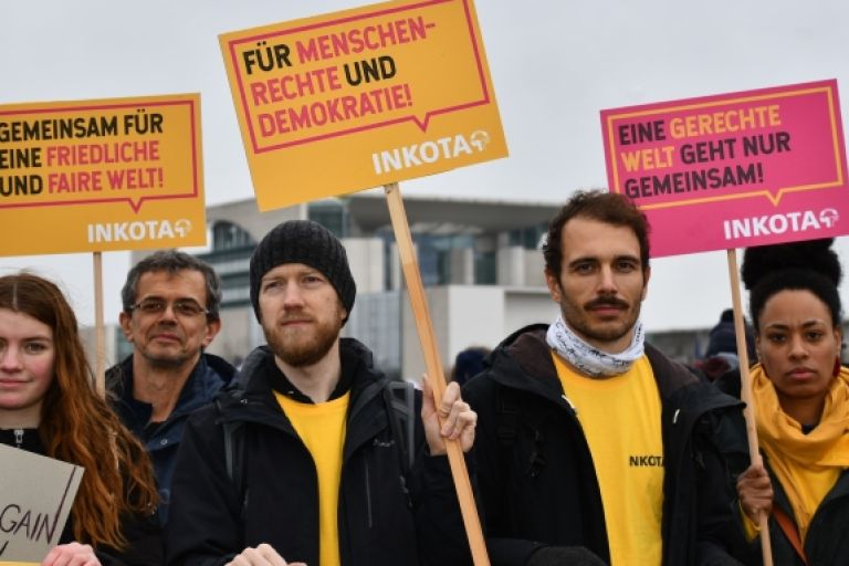 Gruppe von Menschen hält Protestschilder in die Höhe